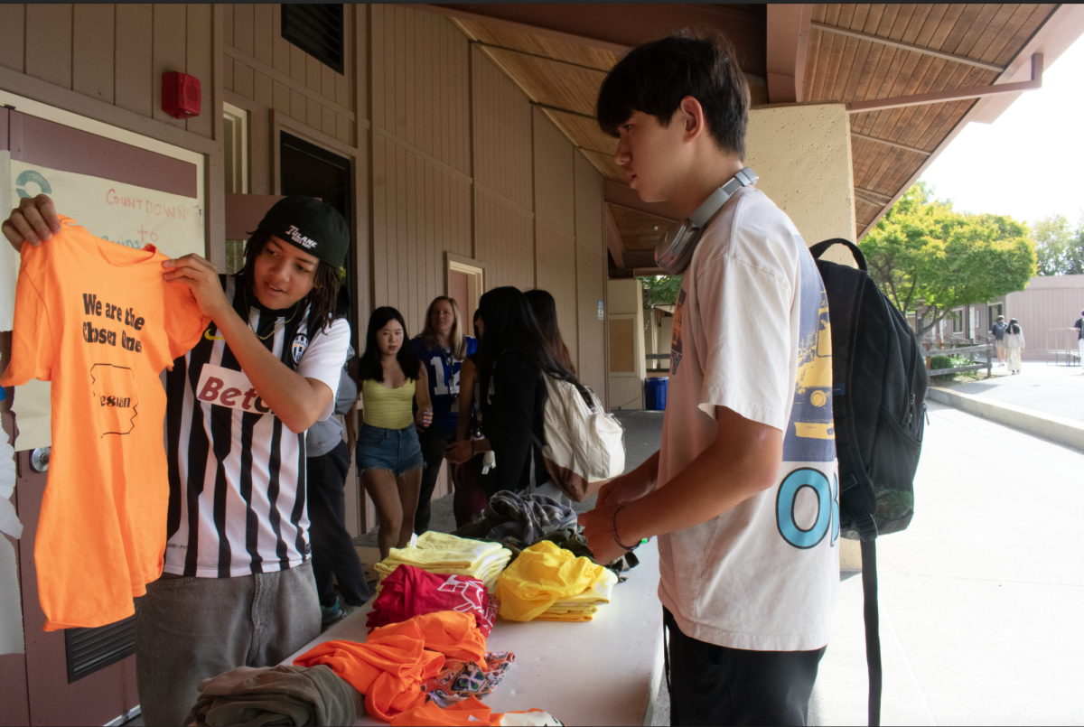 Senior ASB vice president Amani Fossati-Moiane cycles through the donated freshman class spirit shirts in front of room 502 on Thursday to an interested Paly student. "The Spirit Swap was mainly for people who don't necessarily tend to participate much in Spirit Week and don't go out of their way to search for outfits," Fossati-Moiane said. "This was a way to bring Spirit Week shopping to school."